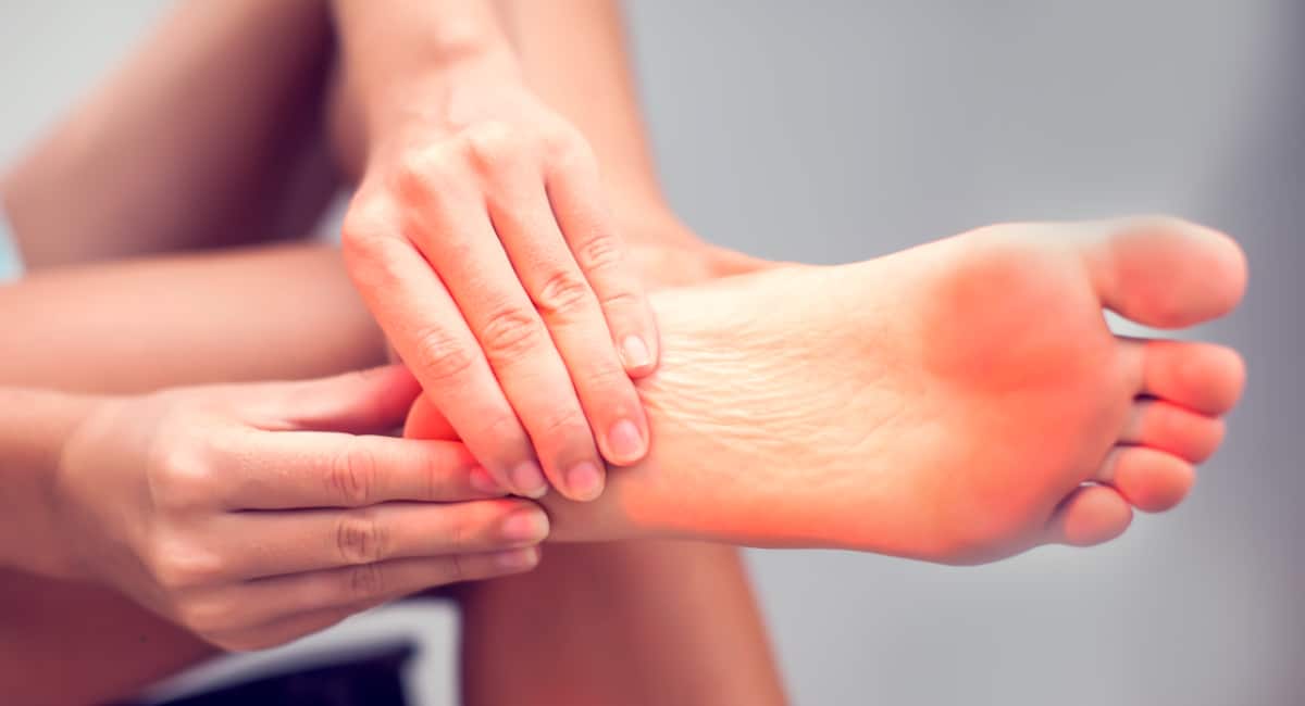 Woman hand holding heel of foot with pain.