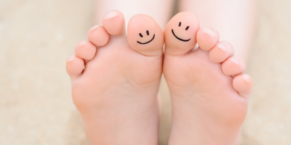 Woman with smiling faces drawn on toes, closeup of foot